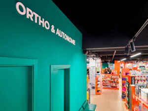 Zone d’orthopédie à la Pharmacie Colombia Lafayette avec mur bleu-vert apaisant et espace d’exposition lumineux, design par Medd Agencement.